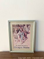 Framed vintage Grape-Nuts poster showing a young girl walking with a Saint Bernard dog holding a basket, with text advertising Grape-Nuts cereal.