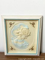 Full view of framed 3D molded plastic wall art showing classical Greek woman in profile, with distressed white frame and blue trim.