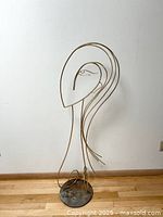 Full view of the wire female sculpture showing its abstract design, brass wire forming head, hair, and figure on a round steel base.