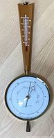 Full view of vintage Airguide barometer and thermometer on wooden backing, showing dial and thermometer clearly.