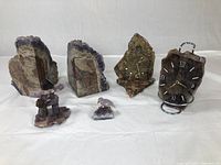 Photo showing entire lot including two amethyst bookends, carved bird, carved Innukshuk, and two agate clocks on white background.