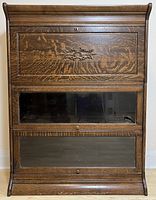 Front view showing all three stacked sections, carved top door, two glass-front doors and visible glass damage on middle section