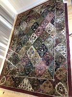 Top view of the rug laid on hardwood floor showing full pattern and fringe.