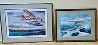 Two framed aviation prints side-by-side on a wall, showing floatplanes in flight.