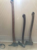 Three axes side by side against wall