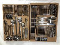 Two trays displaying full set of cutlery and serving pieces