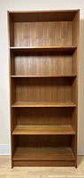 Full front view of teak bookcase showing five shelves, frame and back panel
