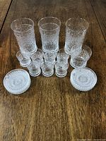 Full set of 3 highball glasses, 7 liqueur glasses, 2 lowball glasses, and 6 coasters arranged on a wooden surface