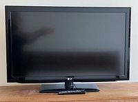 Front view of the LG 42-inch TV on a stand with remotes placed below the screen.