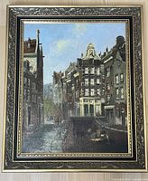 Full view of framed oil painting showing canal scene by European buildings