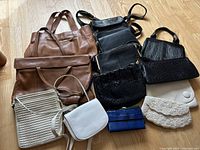 Photo of all 11 assorted purses and handbags laid out on floor showing variety of colors, materials and sizes.