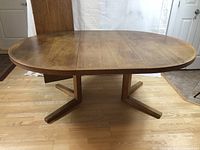 Full view of extended oval table with two leaves inserted, showing X-shaped pedestal base.