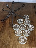 Nine-arm iron chandelier frame and nine glass cups laid out on table