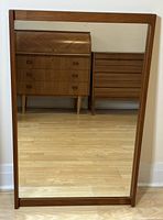 Full front view of the rectangular teak framed mirror showing wood grain and reflection of wooden furniture.