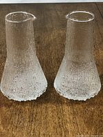 Two Iittala Ultima Thule pitchers side by side on wooden surface
