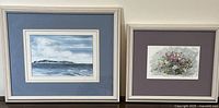 Two framed watercolour paintings side by side, seascape on left, floral on right