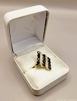 Ring with rows of blue sapphire and white topaz stones set in gold plated silver, presented in white cushioned ring box.