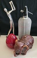 Image showing all four items: vintage seltzer bottle, elephant candle, red glass paperweight, and golfer sculpture