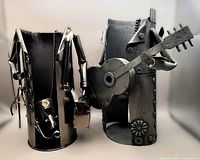 Pair of metal novelty wine holders shaped as humanoid figures playing guitar and saxophone, shown alone.