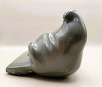 Side view of the dark grey polished stone seal carving showing smooth body and flippers.