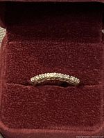 Ring displayed in red velvet box, front view showing diamond row and gold band