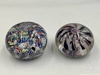 Two handblown glass paperweights side by side on white background