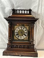 Front view showing full wooden case, columns, dial and decorative top railing