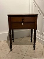 Front view of mahogany side table with two drawers and barley twist legs.