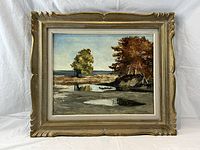 Full view of framed landscape painting showing trees, water and sky