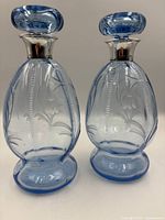 Two blue glass decanters side by side showing shape, color and stoppers