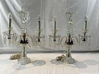 Front angle view of the pair of matching cut glass girandole lamps showing two candle style bulbs and hanging glass prisms attached to the arms.