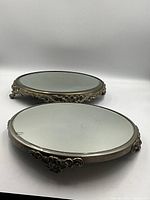 Image showing two oval footed mirror stands with decorative metal frames and antiqued mirror surfaces.
