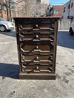 Front view of vintage 5-drawer chest showing ornate carved drawer fronts and wooden knobs.
