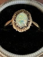 Close-up of ring face showing opal and scalloped gold setting
