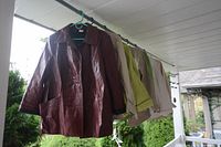 Collection of leather jackets and cotton blazers hanging on a clothesline, showing front views and materials