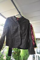 Dark olive green button front blazer jacket hanging outdoors on a hanger