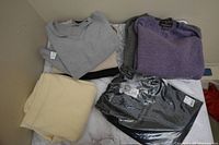 Collection of folded wool and cashmere tops and cream-colored pants on a flat surface