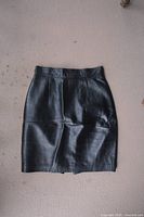 Front view of black leather skirt showing smooth leather material and vertical seam details.