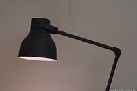 Side profile of the black Ikea Hektar lamp arm and shade, showing the shape and adjustable joint details.