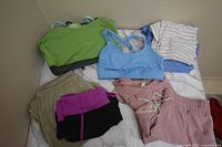 Multiple Lululemon activewear items including sports bras, shorts, tops and pants arranged on a marble surface.
