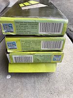 Close-up photo of the box side label showing product specifications: Easy Street Drop Click Vinyl Plank Flooring, Aberdeen color, code FVE5PAA8E, 20.2 sq ft per carton, 4.2 mm thickness, plank dimensions 150 mm x 1220 mm, 10 pieces per carton, production date 2017/07/30.