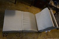Folded and laid out adjustable memory foam wedge pillow in light gray fabric cover on a carpet.