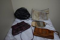 Five vintage eelskin handbags on marble surface showing size and colors