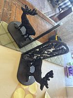 Two black cast iron bookends shown side by side with distinct deer figure and leaf motif panel.