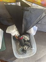 Photo showing vintage camera, black light reflector hood, lenses, and accessories inside a plastic container.