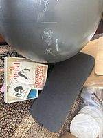 Wide view showing the exercise ball with printed instructions, two fitness books, and black foam roller on a carpeted floor.