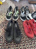 Four pairs of sneakers (black Converse, black Vans with green laces, black Vans with white laces, red Nike) and a Raiders ball cap displayed on carpeted floor.
