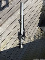 Photo of the Thule aluminum bike rack lying on wooden decking. Shows full length of rack, aluminum body, and black mounts and straps.