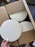Image showing multiple white, round, 8-inch cake boards stacked inside a cardboard box.