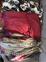 Four shawls displayed including Vince Camuto shawl, black and white floral shawl, deep red shawl with fringe, and multicolored geometric pattern shawl with yellow trim.